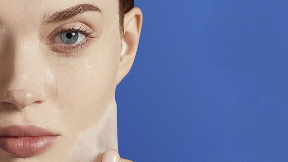 Gesichtshaut, die Maske abzieht, vor blauem Hintergrund.