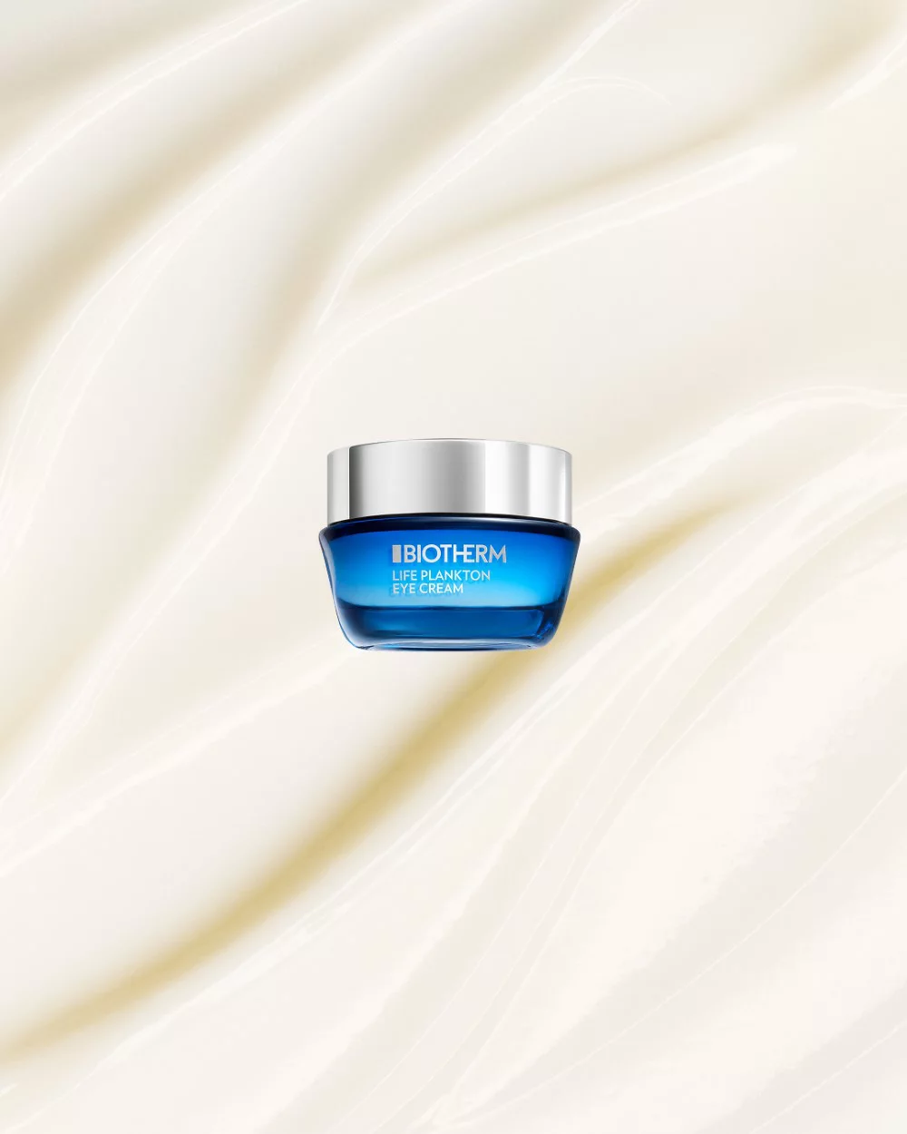 Cremeglas mit silbernem Deckel schwebt vor einem beigen, wellenformigen Hintergrund. Text: "BIOTHERM LIFE PLANKTON EYE CREAM".