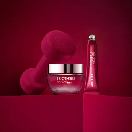 Drei Cremeglaser schweben vor blauem Hintergrund: Links weiß, Mitte blau, Rechts rot. Text: "BIOTHERM".