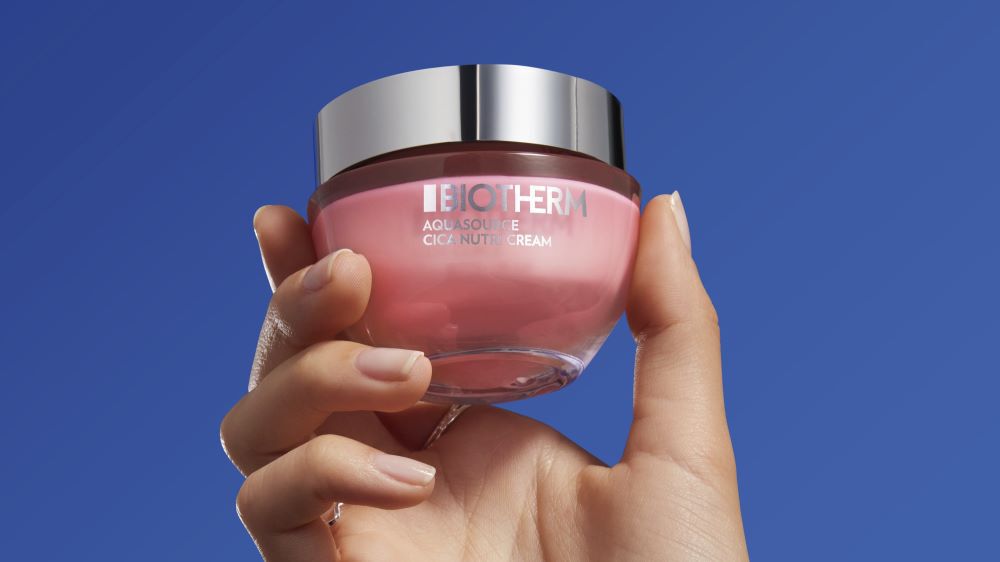 Hand halt rosa Cremetiegel mit Silberdeckel vor blauem Himmel. Text: "BIOTHERM AQUASOURCE CICA NUTRIT CREAM".