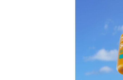 Sonnencremeflasche schwebt vor blauem Himmel mit einigen weißen Wolken.
