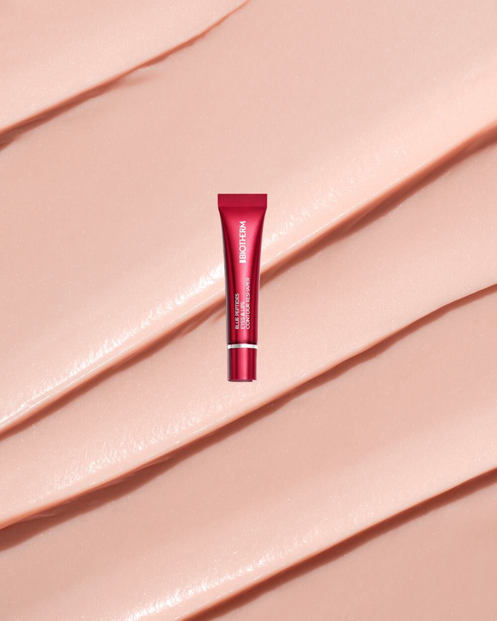Rote Tube steht auf glanzendem, beigem Hintergrund. Text auf Tube: "BIOTHERM BLUE THERAPY EYE CREAM".