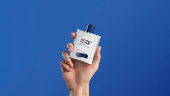 Emulsion apres-rasage dans une main sur fond bleu
