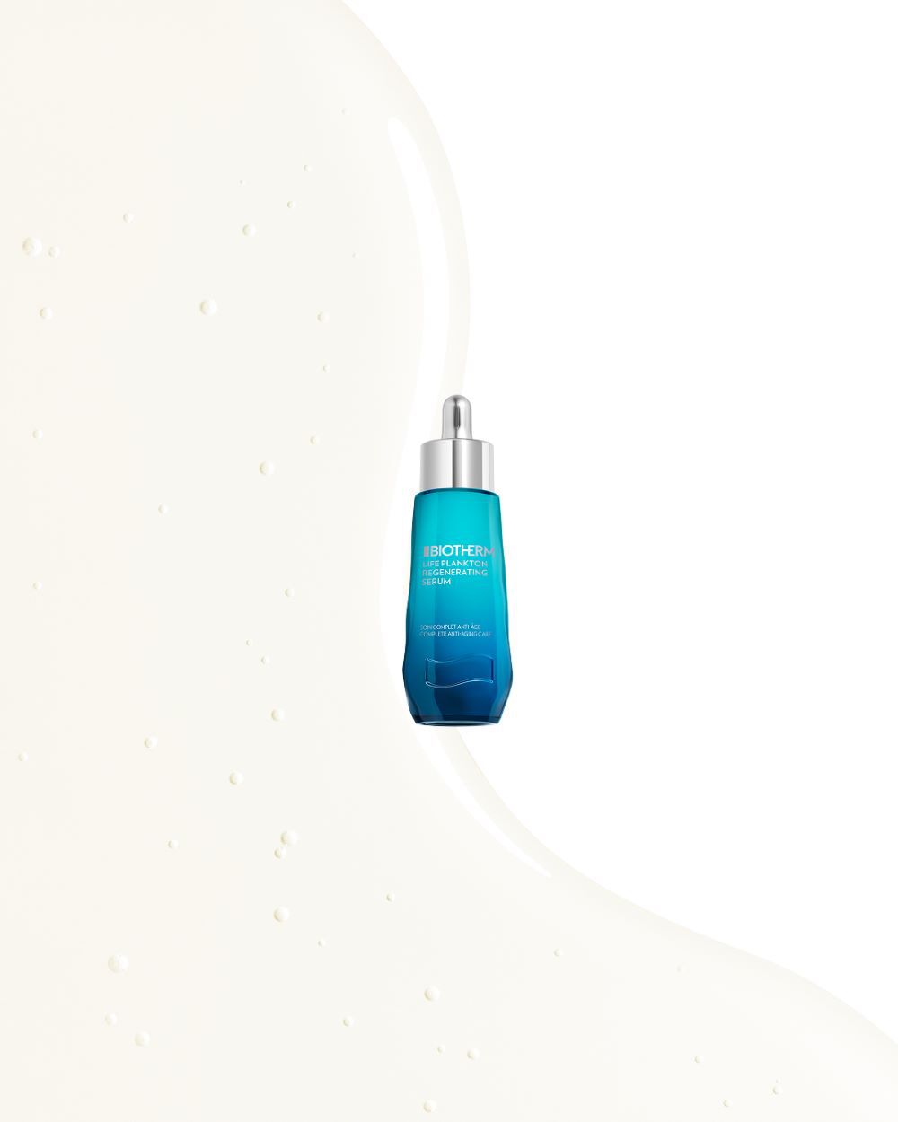 Ein blaues Serumflaschchen mit Pipette auf cremefarbenem, strukturiertem Hintergrund. Text: "BIOTHERM LIFE PLANKTON REGENERATING SERUM CONCENTRATED ANTI-AGE COMPLETE INTERVENTION".