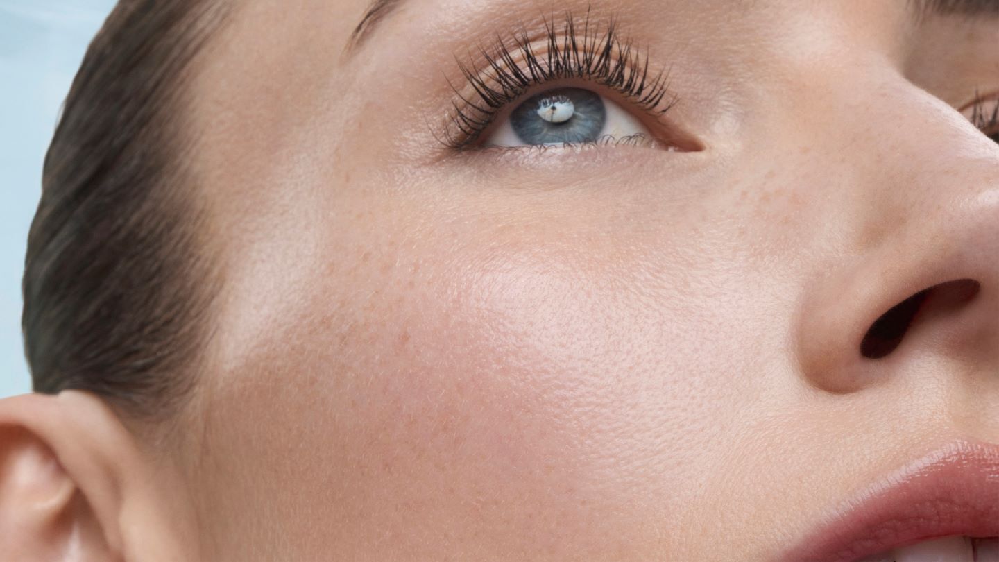 Gesicht in Nahaufnahme mit blauem Auge, nach oben schauend; helle Haut, glatter Teint.