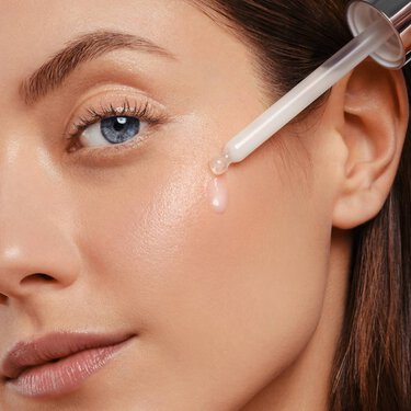 Femme qui applique un serum sur son visage