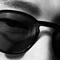 Brille sitzt auf Nase, zwei Augen schauen durch getonte Glaser, Nahaufnahme in Schwarz-Weiß.