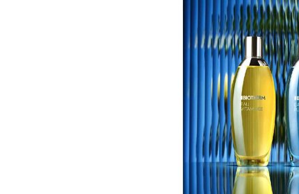 Zwei Flaschen Parfum stehen vor einem wellenformigen blauen Hintergrund. Text: BIOTHERM EAU D'ENERGIE.