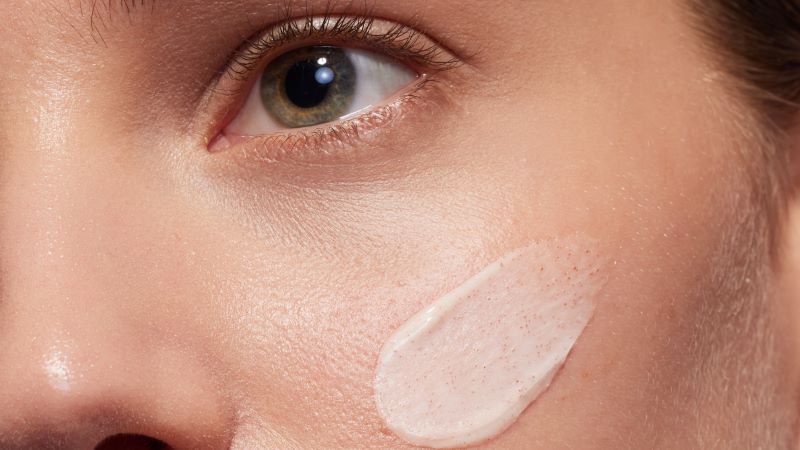 Gesicht mit Creme auf Wange, nahes Detail, Fokus auf Hautpflege und Textur.