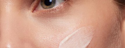 Gesicht mit Creme auf Wange, nahes Detail, Fokus auf Hautpflege und Textur.