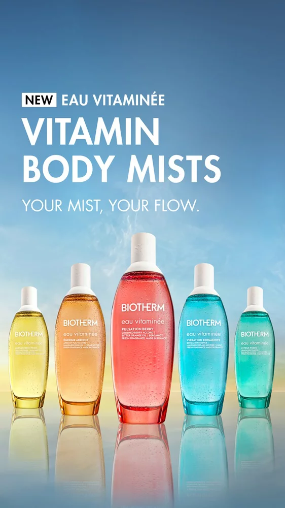 Five colorful Biotherm Eau Vitaminee body mist bottles lined up against a soft blue and yellow gradient background, with the text: “NEW Eau Vitaminee – Vitamin Body Mists. Your mist, your flow.”