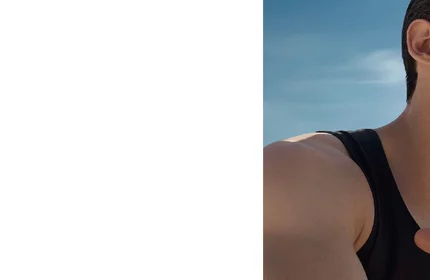 Person mit schwarzen Tanktop vor blauem Himmel, oberen Korper und Arm zeigend.