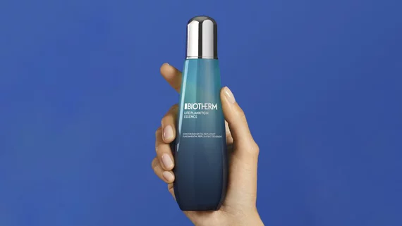 Hand halt eine Biotherm-Flasche vor blauem Hintergrund. Text: "BIOTHERM LIFE PLANKTON ESSENCE".