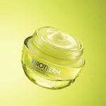 Transparente Flasche und gelbe Tube Biotherm Aquasource+ Eau de Lait Demaquillante mit sichtbaren Wassertropfen vor leuchtend grunem Hintergrund.