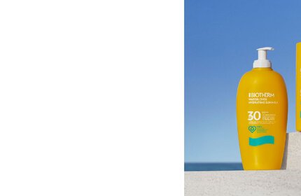 Gelbe Sonnencremeflasche mit blauem Logo steht auf einer Mauer vor blauem Himmel und Meereshorizont. Text: "BIOTHERM. Waterlover Hydrating Sun Milk SPF30. 400ml."
