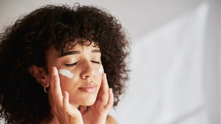 Young woman with cream on both cheeks