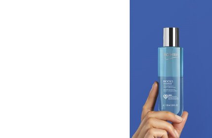 Hand halt blaue Flasche mit silbernem Deckel vor blauem Hintergrund, darauf steht: "BIOTHERM BIOCILS".