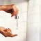 Pipette tropft Serum auf die Finger einer Hand, vor einem hellen Hintergrund mit Vorhangen.