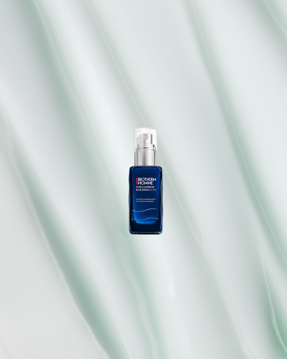 Eine blaue Lotionflasche mit Spender vor einem weißen, welligen Hintergrund. Text: "BIOTHERM HOMME FORCE SUPREME BLUE SERUM-IN-LOTION."