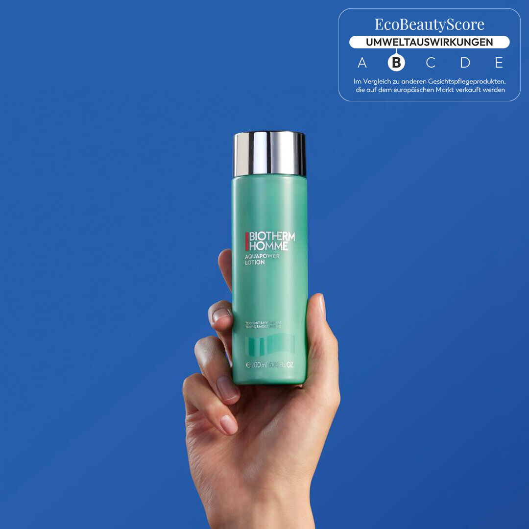 Hand halt eine grune Flasche vor blauem Hintergrund. Keine weiteren Textinformationen vorhanden.