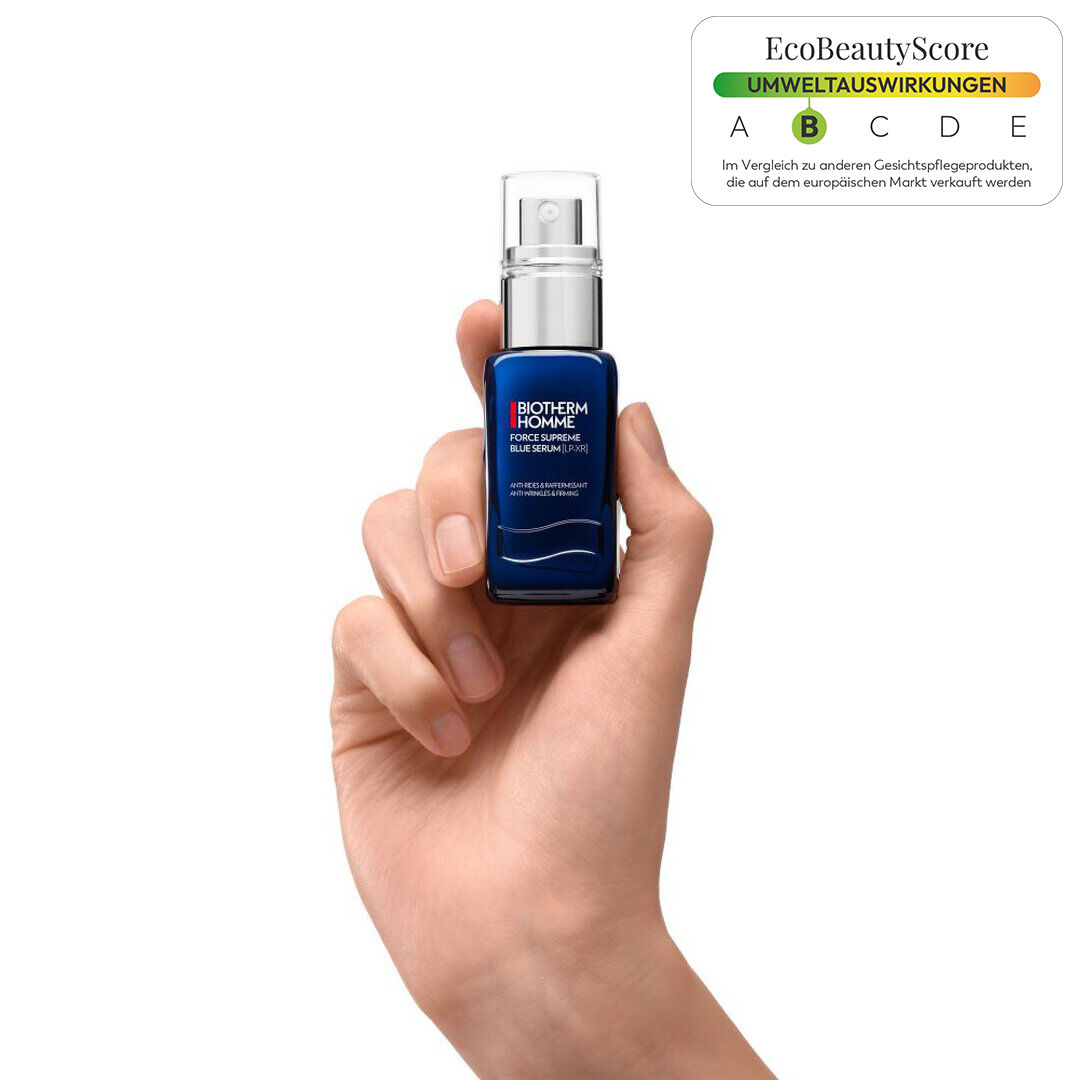 Eine Hand halt eine blaue Flasche-Serum mit weißer Aufschrift auf weißem Hintergrund.