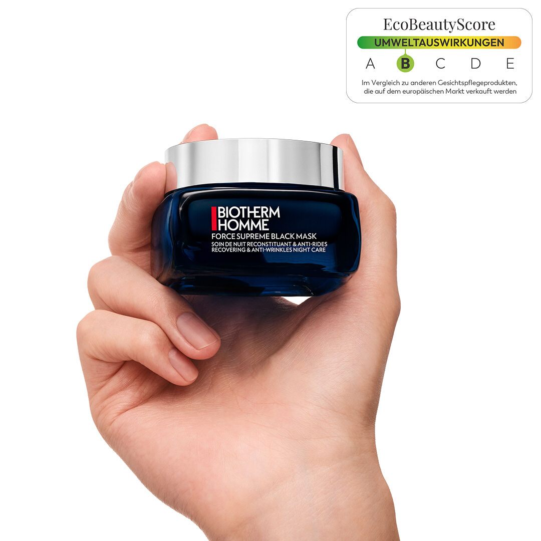 Hand halt einen blauen Creme-Tiegel mit silbernem Deckel vor blauem Hintergrund.