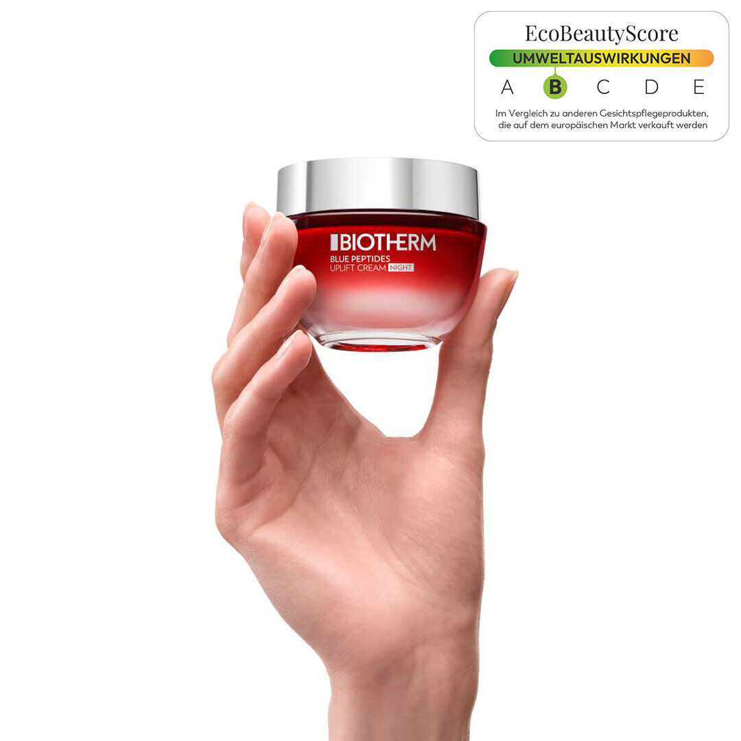 Eine Hand halt ein Glas mit roter Creme, umgeben von weißem Hintergrund.