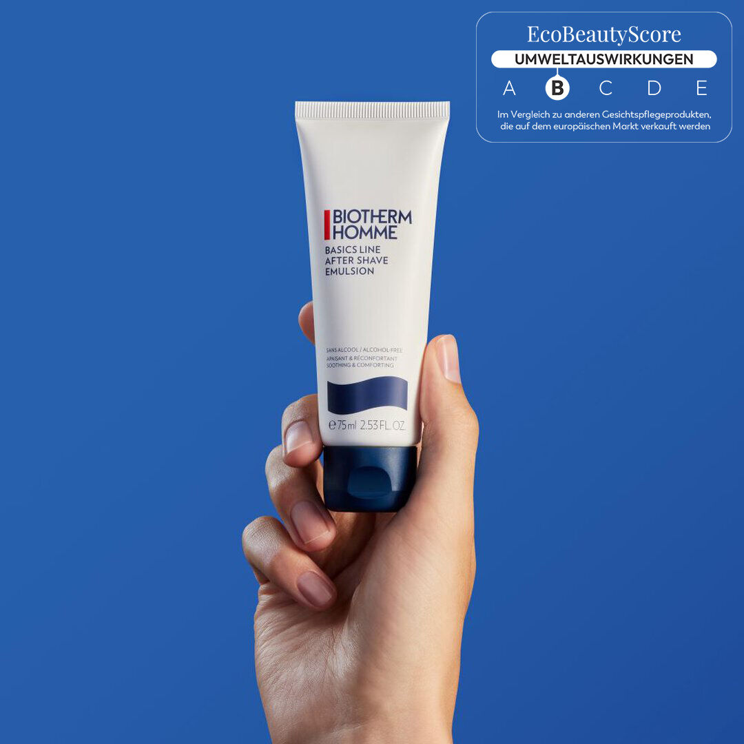 Eine Hand halt eine Flasche Hautcreme vor einem blauen Hintergrund.
