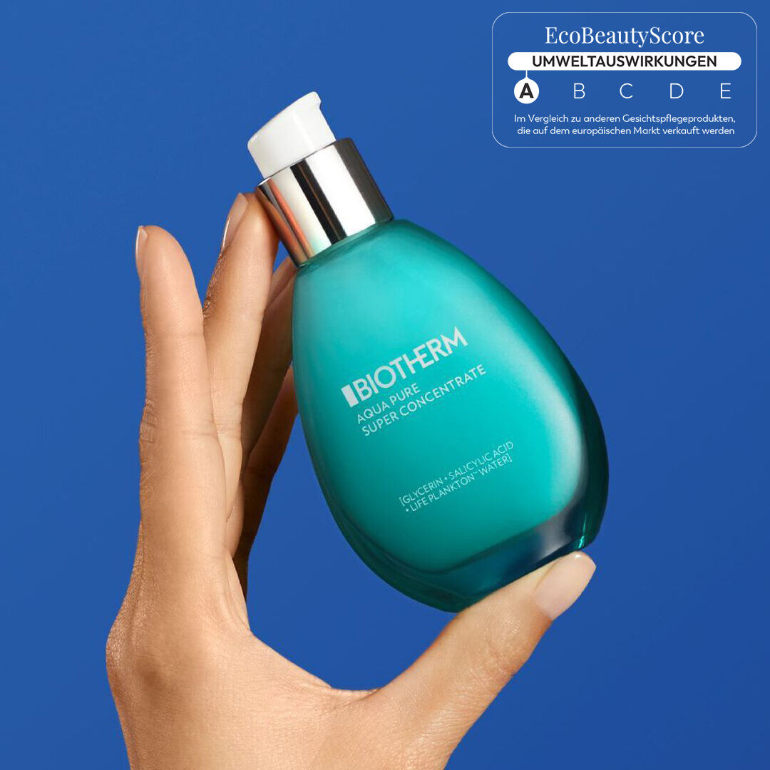 Eine Hand halt eine turkisfarbene Flasche mit der Aufschrift „SKIN PROUD REFRESH“, vor blauem Hintergrund.