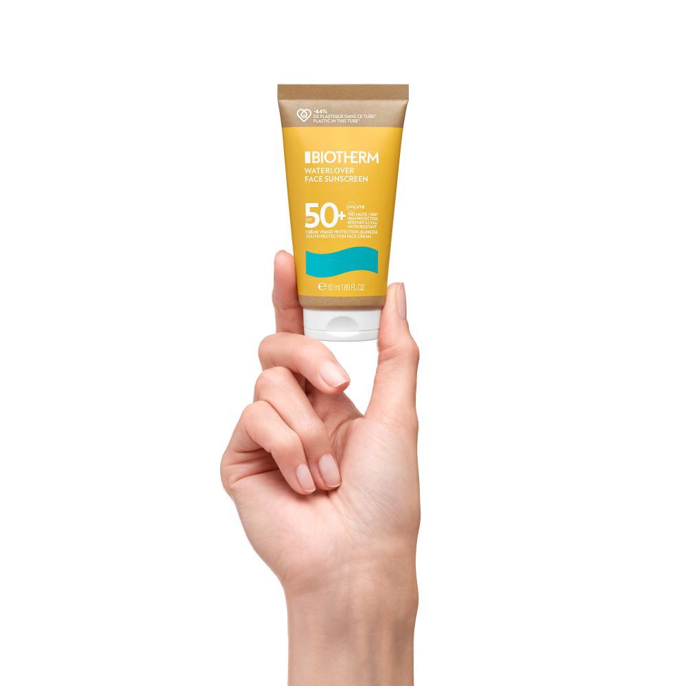 Hand halt eine gelbe Tube mit Sonnenschutz vor weißem Hintergrund.