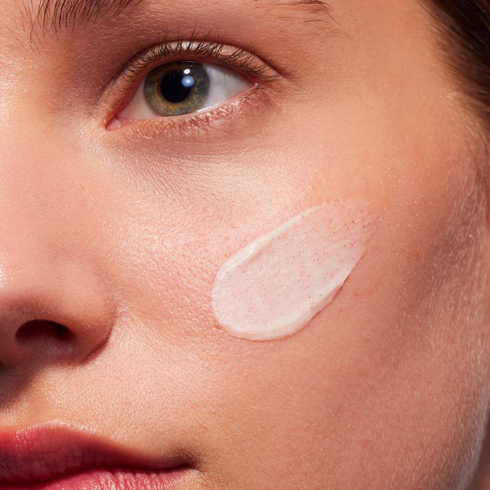 Gesicht mit Creme auf Wange, nah aufgenommen, in heller Umgebung.