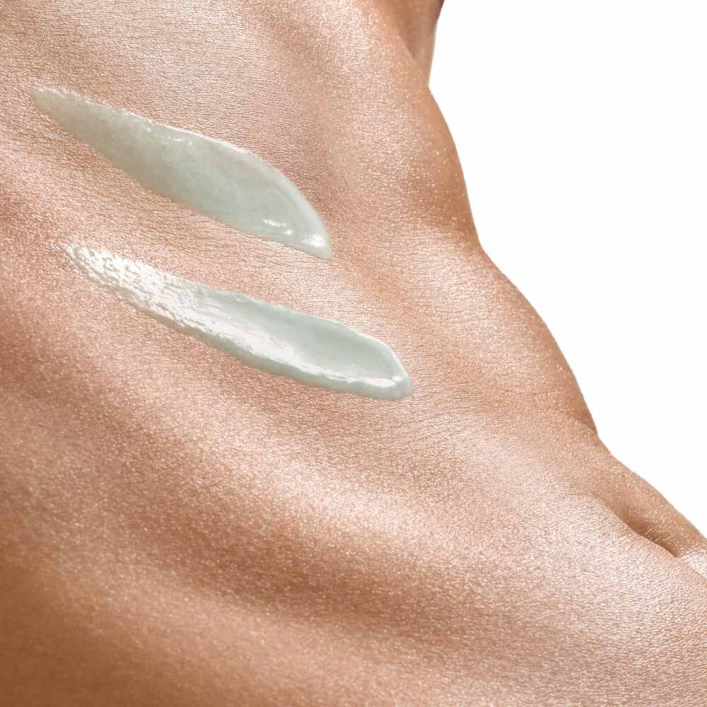 Haut mit zwei Cremestreifen, aufgetragen auf einem Arm, vor einem weißen Hintergrund.