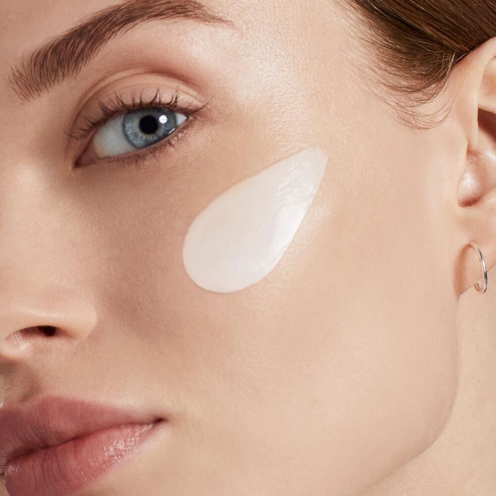 Creme wird auf eine Wange eines weiblichen Gesichts aufgetragen, Nahaufnahme, glatte Haut.