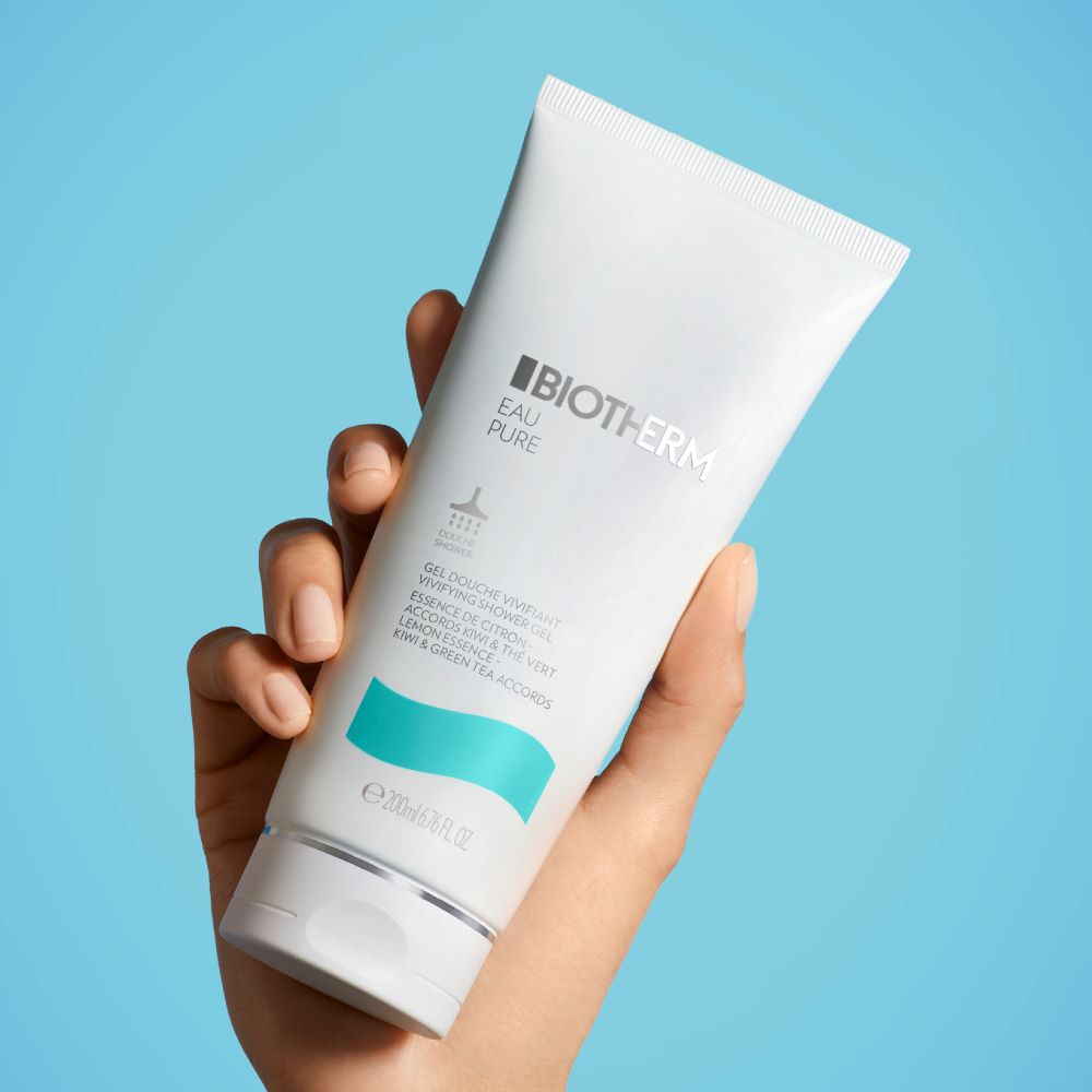 Hand halt Tube mit Hautpflegeprodukt vor blauem Hintergrund.