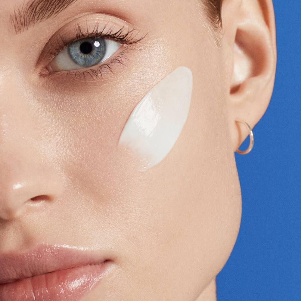 Gesicht mit Cremefleck, blaue Augen, blauer Hintergrund.