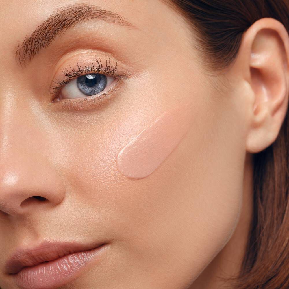 Ein Gesicht zeigt einen Teil eines Auges mit blauem Irismuster in Nahaufnahme, neutrale Mimik.