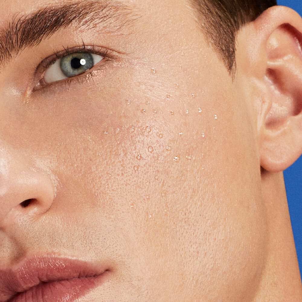 Nahaufnahme eines Gesichts mit hellem Teint vor blauem Hintergrund.