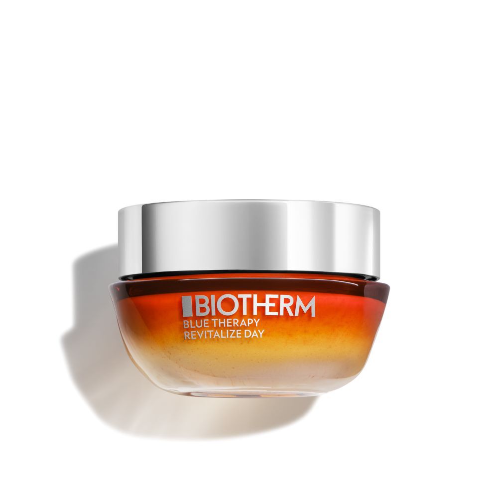 Ein runder Kosmetiktiegel mit silbernem Deckel, Orange-Ton, Markenname "Biotherm" im Studio.