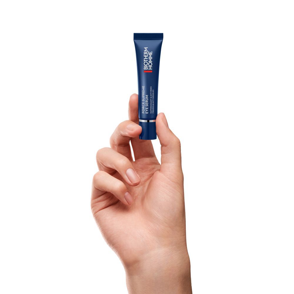 Eine Hand halt eine kleine blaue Tube vor weißem Hintergrund.