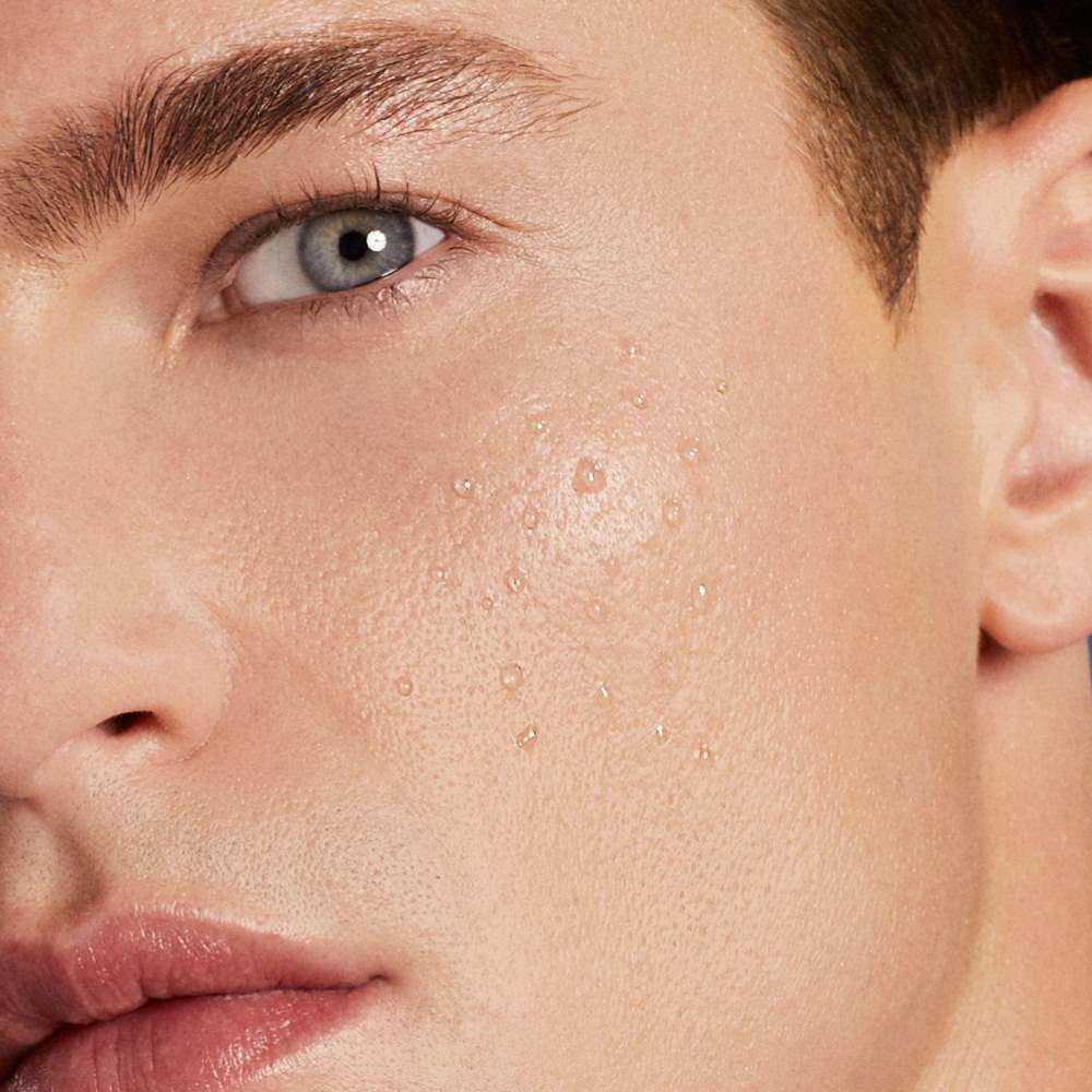 Gesichtsausschnitt eines Mannes; neutrale Miene, Fokus auf Auge; Nahaufnahme, Studiohintergrund.