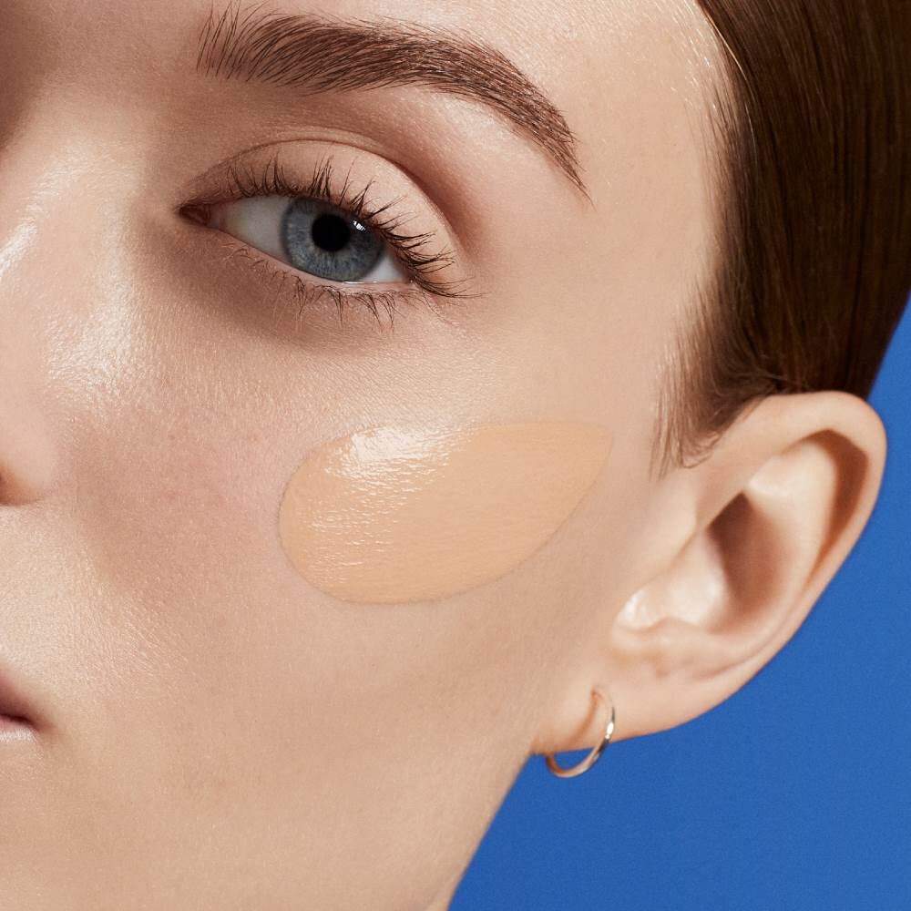 Gesicht mit glanzender Haut vor blauem Hintergrund.